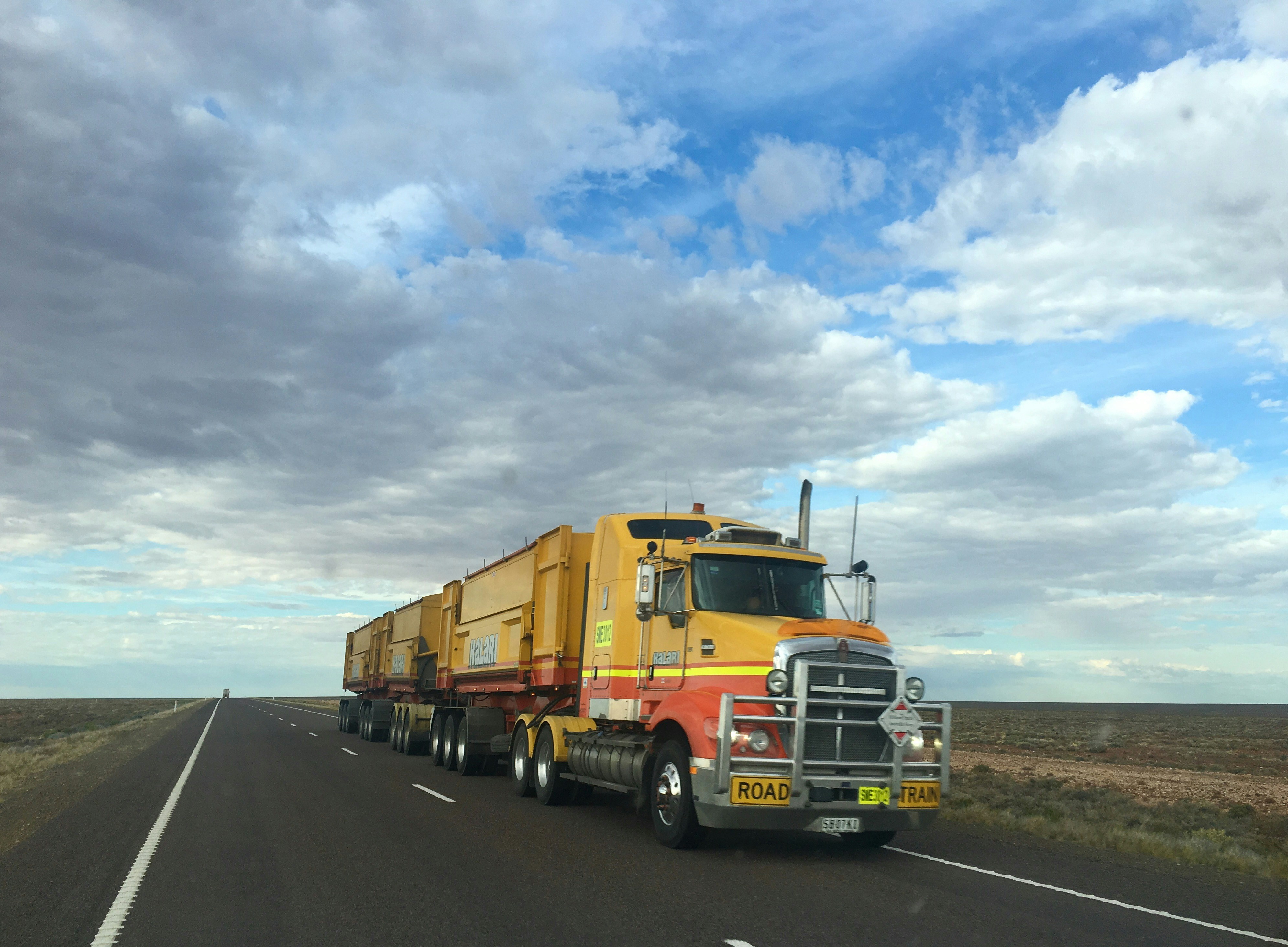 A yellow truck on an open desert road that was dispatched by a Freight Broker