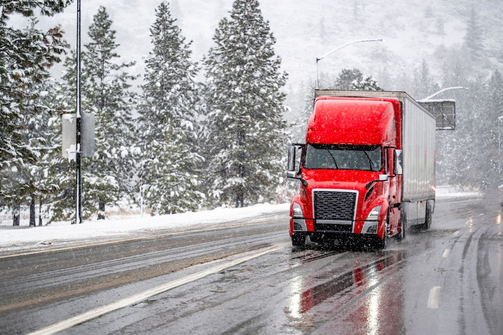 A red semi truck driving on a winter road