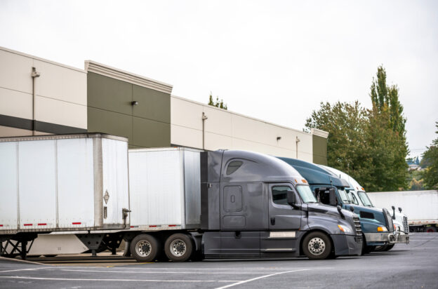 An image of a semi-truck parked at a loading dock, depicting the logistical process including lumper fees in trucking operations